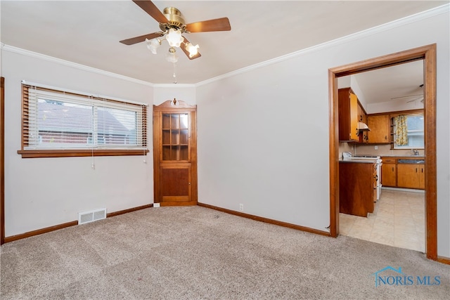 empty room featuring light carpet, ceiling fan, crown molding, and sink