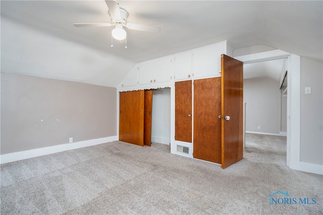 unfurnished bedroom with ceiling fan, a closet, light carpet, and vaulted ceiling