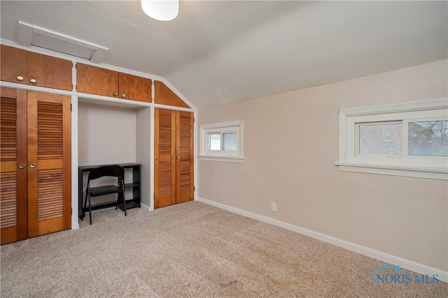 unfurnished bedroom featuring a closet, light colored carpet, and vaulted ceiling