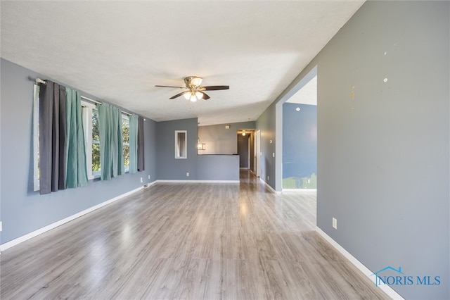 unfurnished living room with ceiling fan, a textured ceiling, and light hardwood / wood-style floors