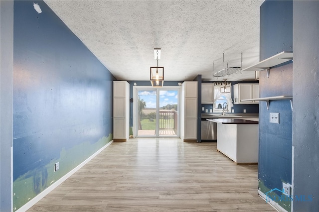 kitchen featuring light hardwood / wood-style floors, decorative light fixtures, a textured ceiling, and white cabinetry