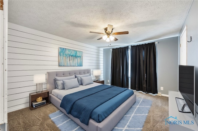 carpeted bedroom with wooden walls, ceiling fan, and a textured ceiling