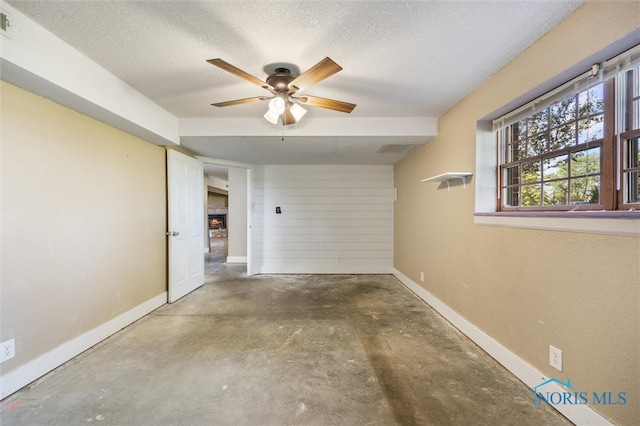 interior space featuring ceiling fan, a textured ceiling, and concrete floors