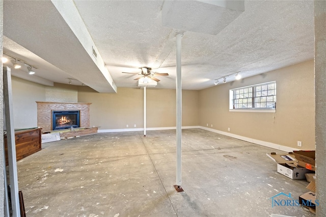 basement featuring ceiling fan, a textured ceiling, and track lighting