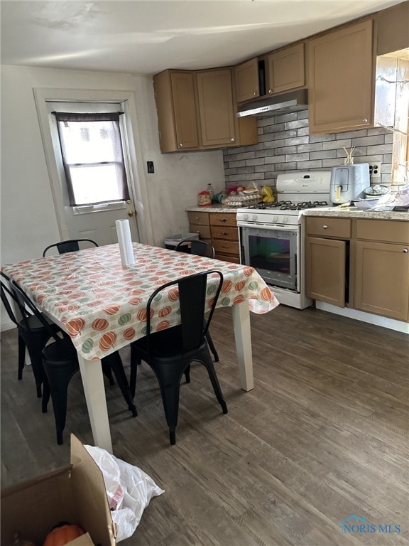 kitchen with decorative backsplash, white range with gas cooktop, dark hardwood / wood-style flooring, and light stone countertops