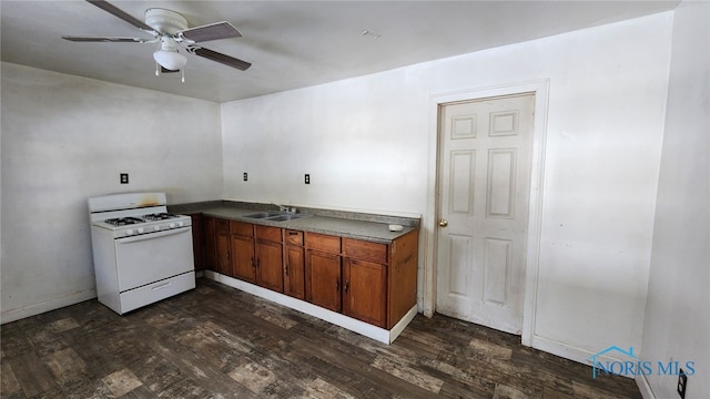 kitchen featuring white gas range oven, dark hardwood / wood-style floors, ceiling fan, and sink