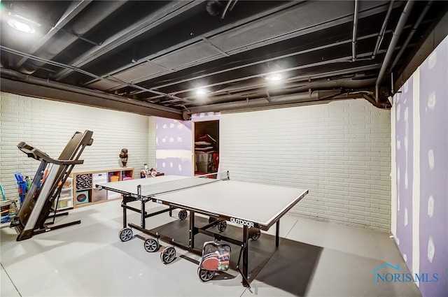 game room featuring concrete floors and brick wall