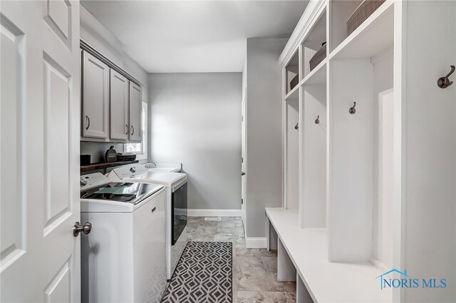 laundry room with washing machine and clothes dryer and cabinets