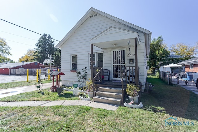 bungalow-style home with a front yard and covered porch