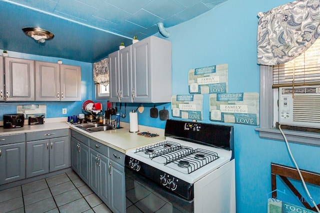 kitchen featuring white gas range, gray cabinets, a healthy amount of sunlight, and light tile patterned floors