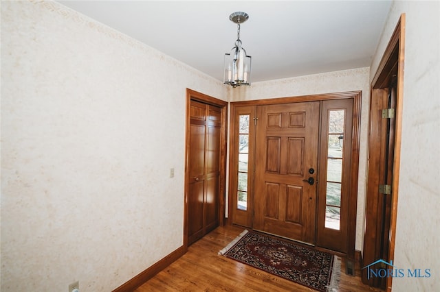 foyer with an inviting chandelier and hardwood / wood-style flooring