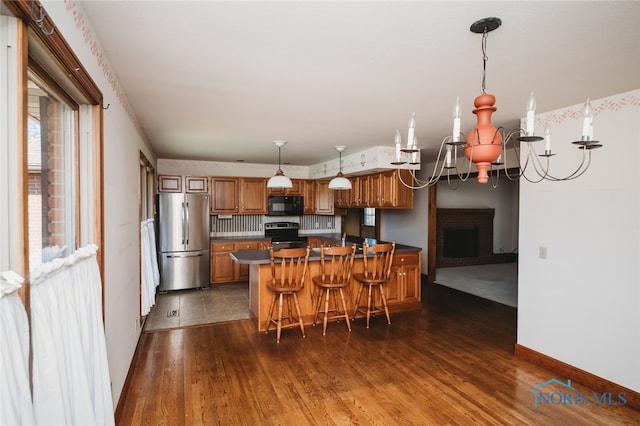 kitchen featuring a notable chandelier, a kitchen bar, dark hardwood / wood-style flooring, and black appliances