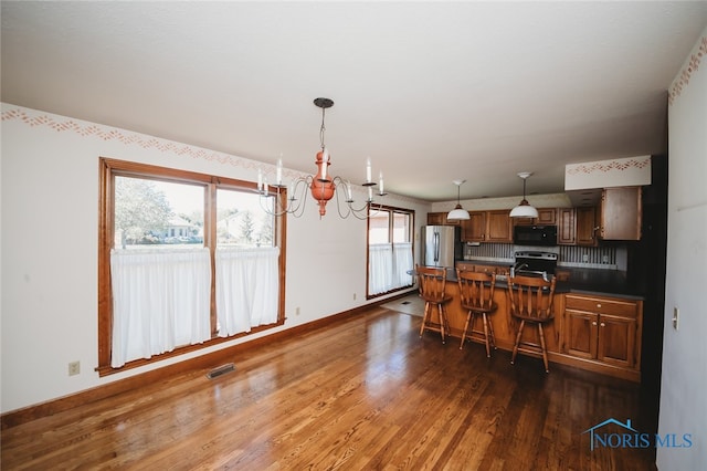 kitchen featuring appliances with stainless steel finishes, plenty of natural light, dark hardwood / wood-style floors, and a kitchen breakfast bar