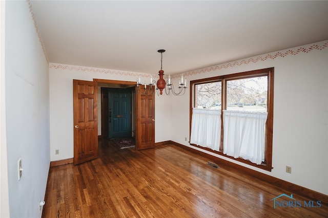 unfurnished dining area featuring dark hardwood / wood-style floors and a chandelier