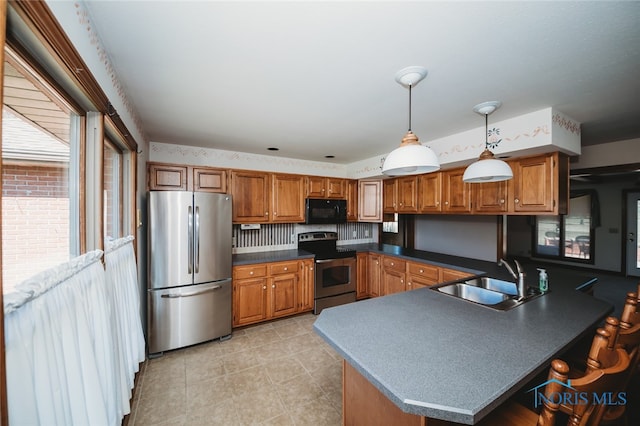 kitchen with decorative light fixtures, stainless steel appliances, sink, and kitchen peninsula