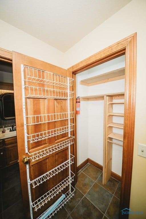 walk in closet with sink and dark tile patterned flooring