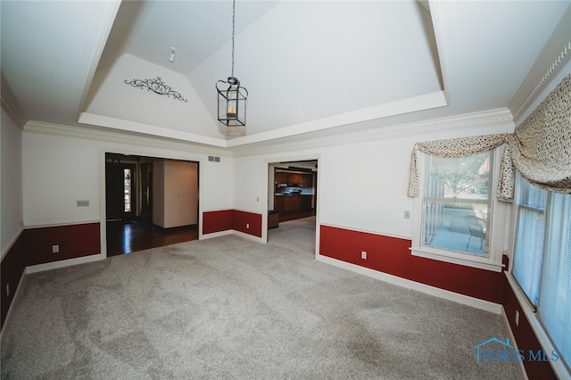 interior space featuring vaulted ceiling, a raised ceiling, crown molding, and carpet flooring