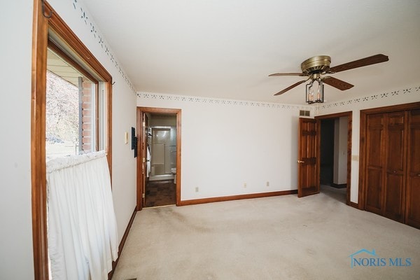 unfurnished bedroom with connected bathroom, ceiling fan, and light colored carpet