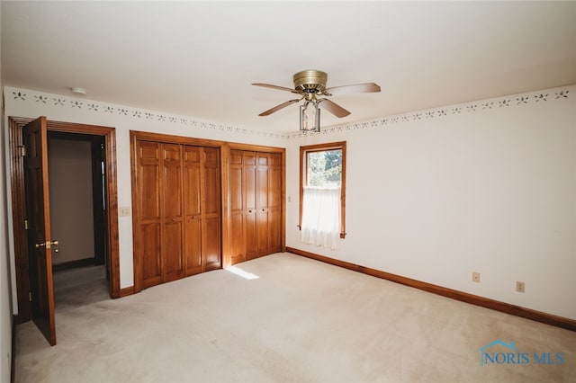 unfurnished bedroom featuring light carpet, two closets, and ceiling fan