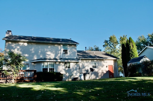 rear view of property featuring a yard and a wooden deck