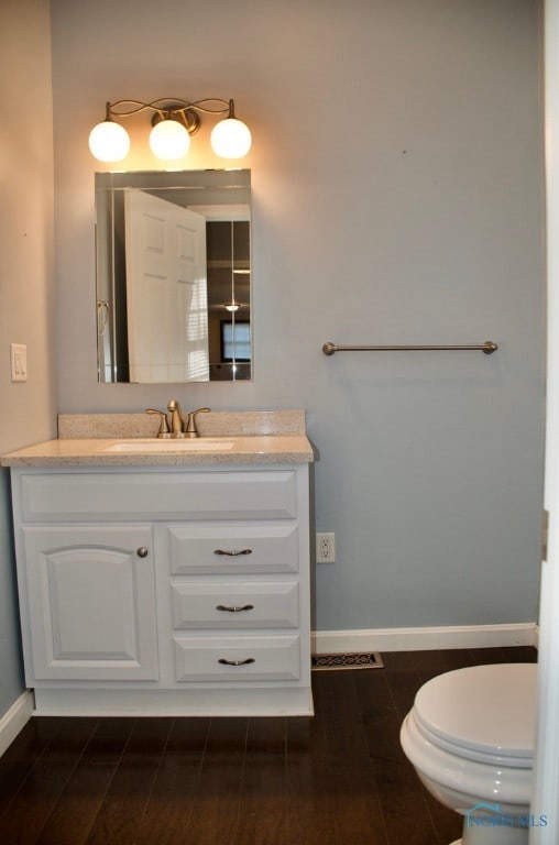 bathroom with wood-type flooring, vanity, and toilet