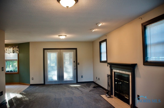 interior space featuring a textured ceiling, a healthy amount of sunlight, and a tiled fireplace