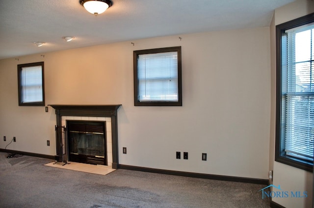 unfurnished living room with a tile fireplace, carpet, and a textured ceiling