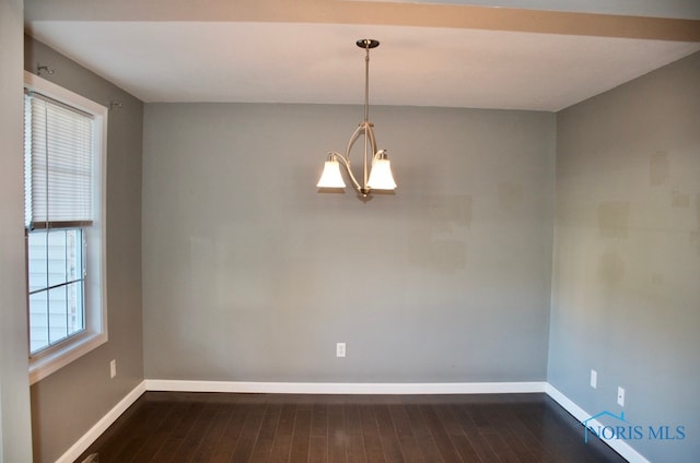 unfurnished room with an inviting chandelier, plenty of natural light, and dark wood-type flooring