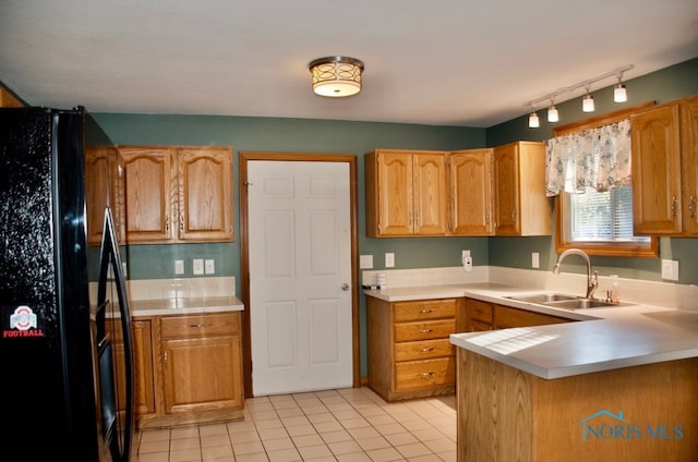 kitchen featuring black fridge, sink, kitchen peninsula, rail lighting, and light tile patterned floors