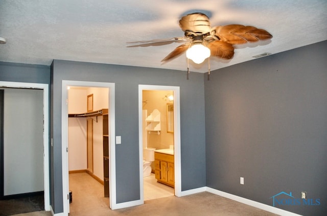 unfurnished bedroom featuring ceiling fan, ensuite bathroom, and a textured ceiling