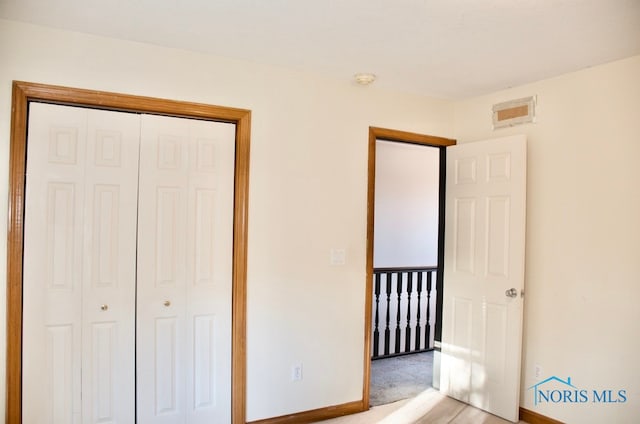 unfurnished bedroom featuring light colored carpet and a closet