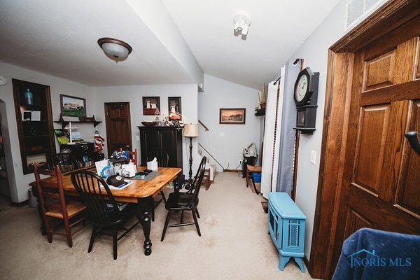 carpeted dining space featuring vaulted ceiling