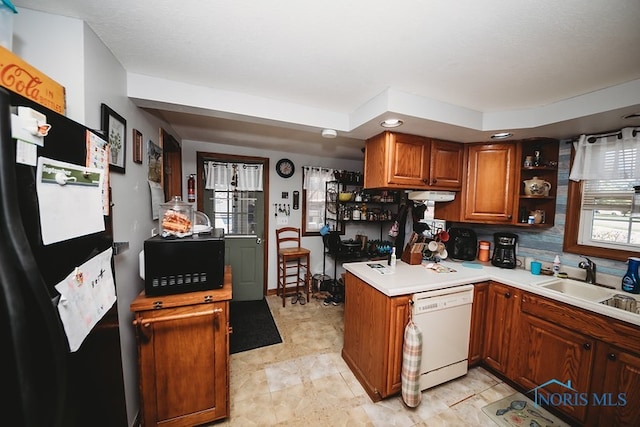 kitchen with dishwasher, sink, kitchen peninsula, backsplash, and black refrigerator