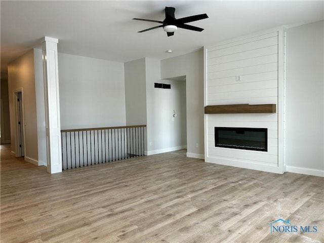 unfurnished living room with ceiling fan, a fireplace, and light hardwood / wood-style flooring