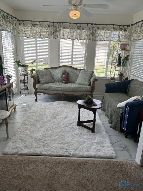 carpeted living room featuring ceiling fan and a wealth of natural light