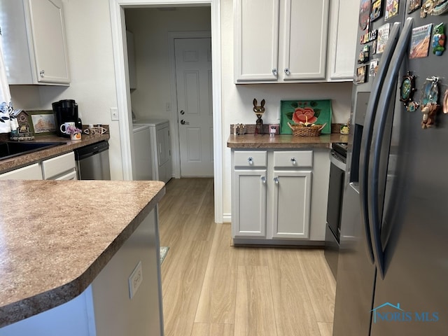 kitchen featuring independent washer and dryer, white cabinets, stainless steel appliances, and light hardwood / wood-style flooring