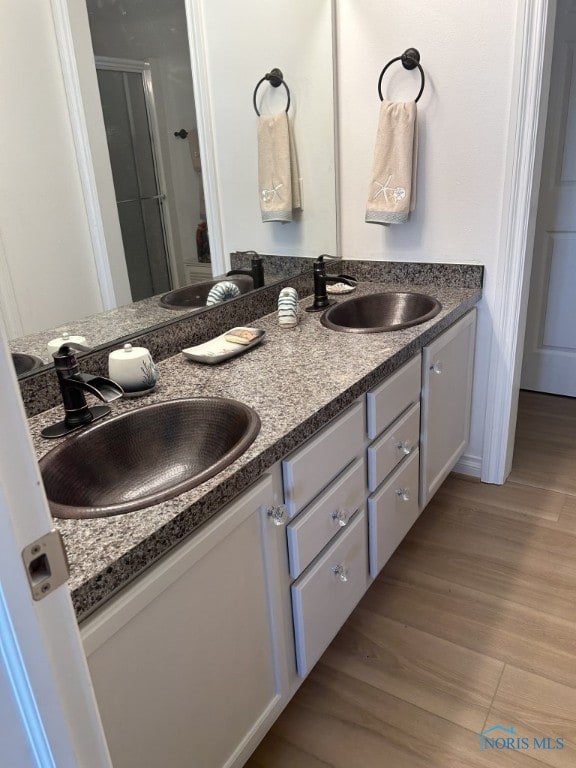 bathroom featuring hardwood / wood-style floors, vanity, and a shower with shower door