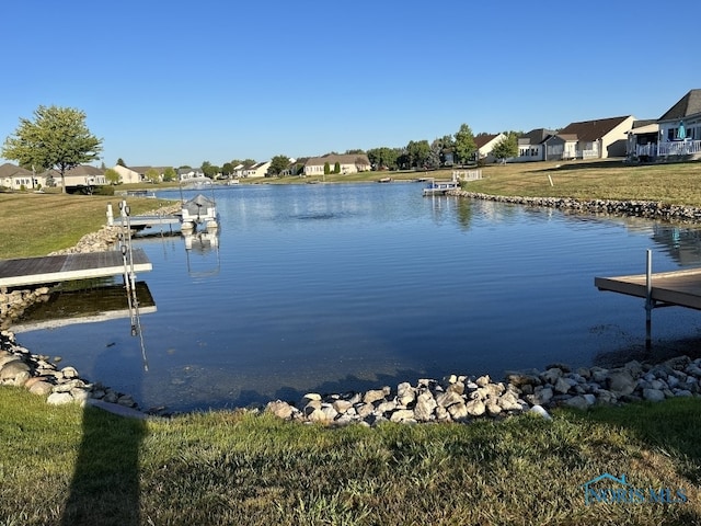 view of dock with a water view and a yard