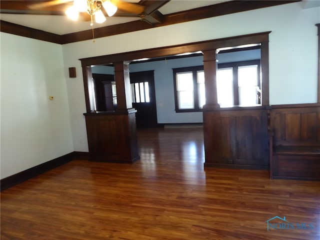 unfurnished room featuring dark wood-type flooring, ceiling fan, and decorative columns