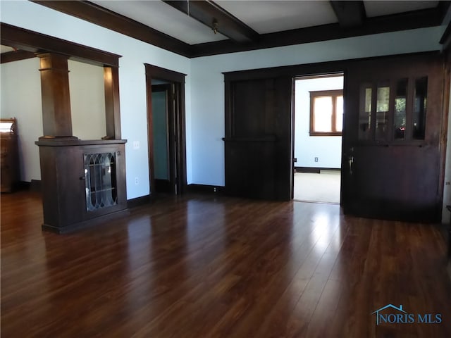 unfurnished living room with dark wood-type flooring, beamed ceiling, and ornate columns