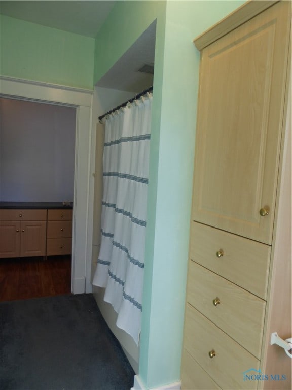 bathroom with shower / tub combo with curtain and wood-type flooring