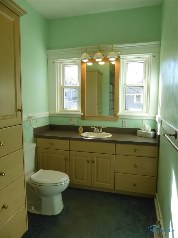 bathroom featuring a wealth of natural light, vanity, and toilet