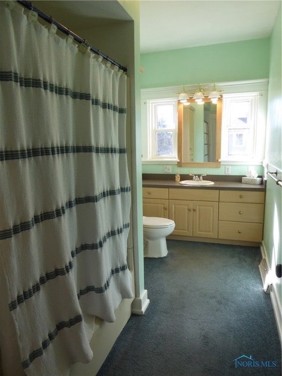 bathroom featuring toilet, vanity, and a shower with shower curtain