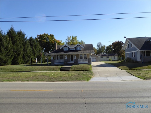 view of front of house featuring covered porch, a garage, and a front yard