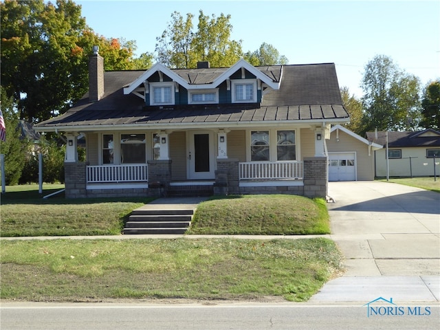 view of front of house with a front yard, a garage, and covered porch