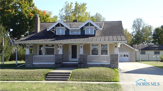 view of front of house with an outbuilding, a garage, a front lawn, and covered porch