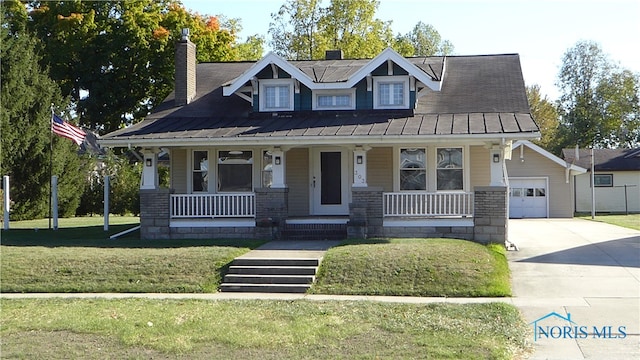 view of front facade featuring covered porch, a garage, an outdoor structure, and a front lawn