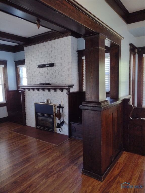 interior space featuring ornate columns, dark hardwood / wood-style flooring, ornamental molding, and beamed ceiling