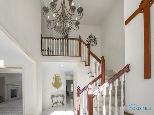 stairs featuring a notable chandelier, tile patterned floors, and a high ceiling