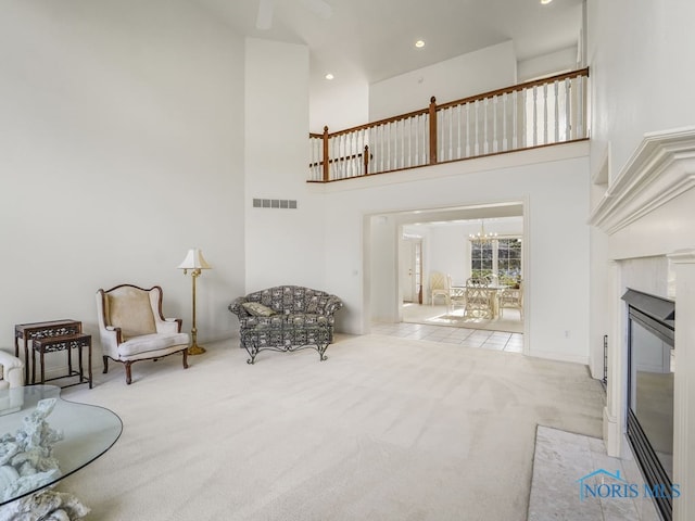 sitting room with a high ceiling, light colored carpet, and a chandelier